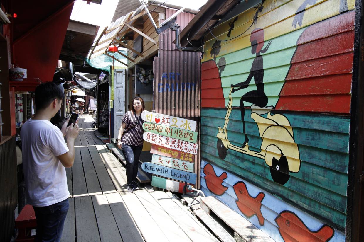 Tourist taking photographs with a mural at Chew Jetty in George Town, Penang. LIM BENG TATT/The Star