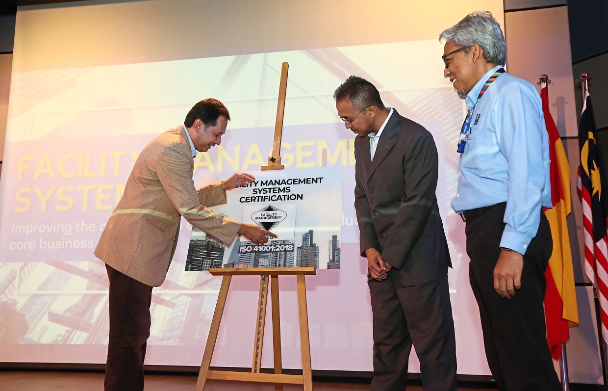 Certification scheme: Mohd Azanuddin (left) unveils the ISO 41001:2018 Facility Management System certification scheme at its launch, while Tun Masri (centre) and SIRIM QAS International management system certification department senior general manager Mohd Hamim Imam Mustain look on.