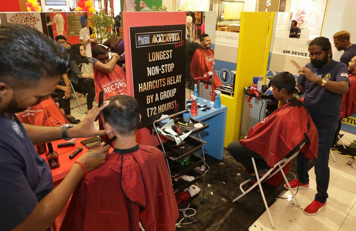 The barbers at work during their non-stop relay haircuts at Gurney Plaza in Penang. ZHAFARAN NASIB/The Star