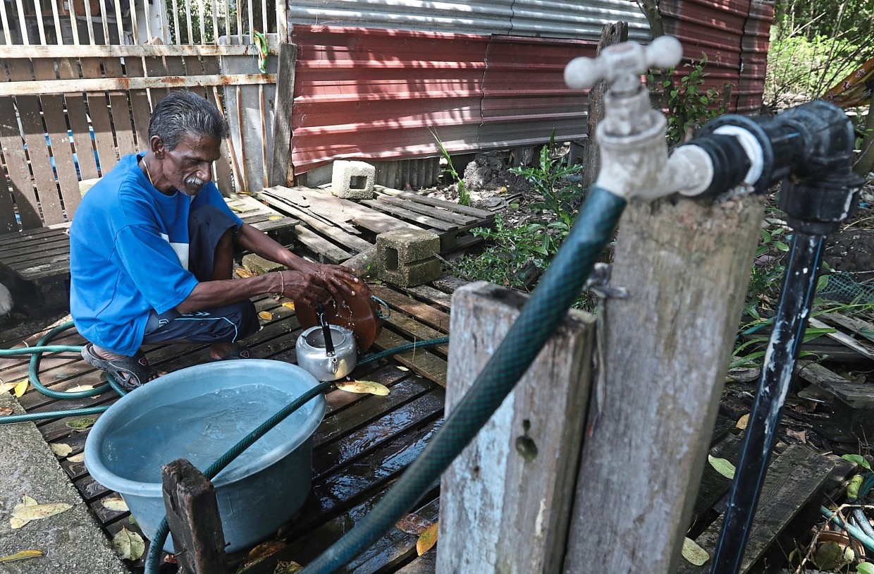 Grass cutter R. Gunasegaran, 50, has to fetch water from his neighbour’s house in Kampung Manis, Penang. — ZHAFARAN NASIB/The Star