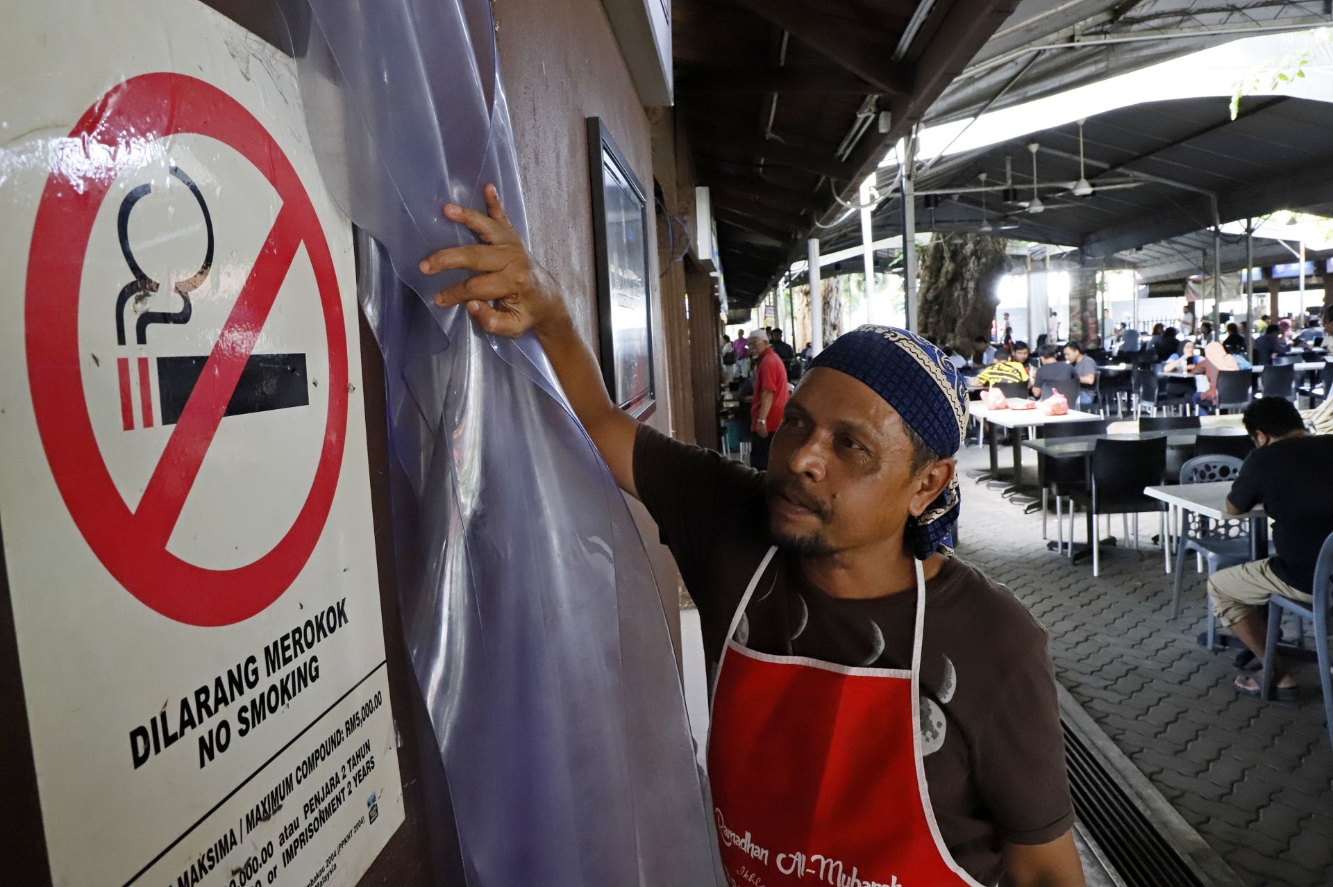 The ruling stays: A stall owner at the Esplanade in George Town, Penang showing a no-smoking sign at his stall.
