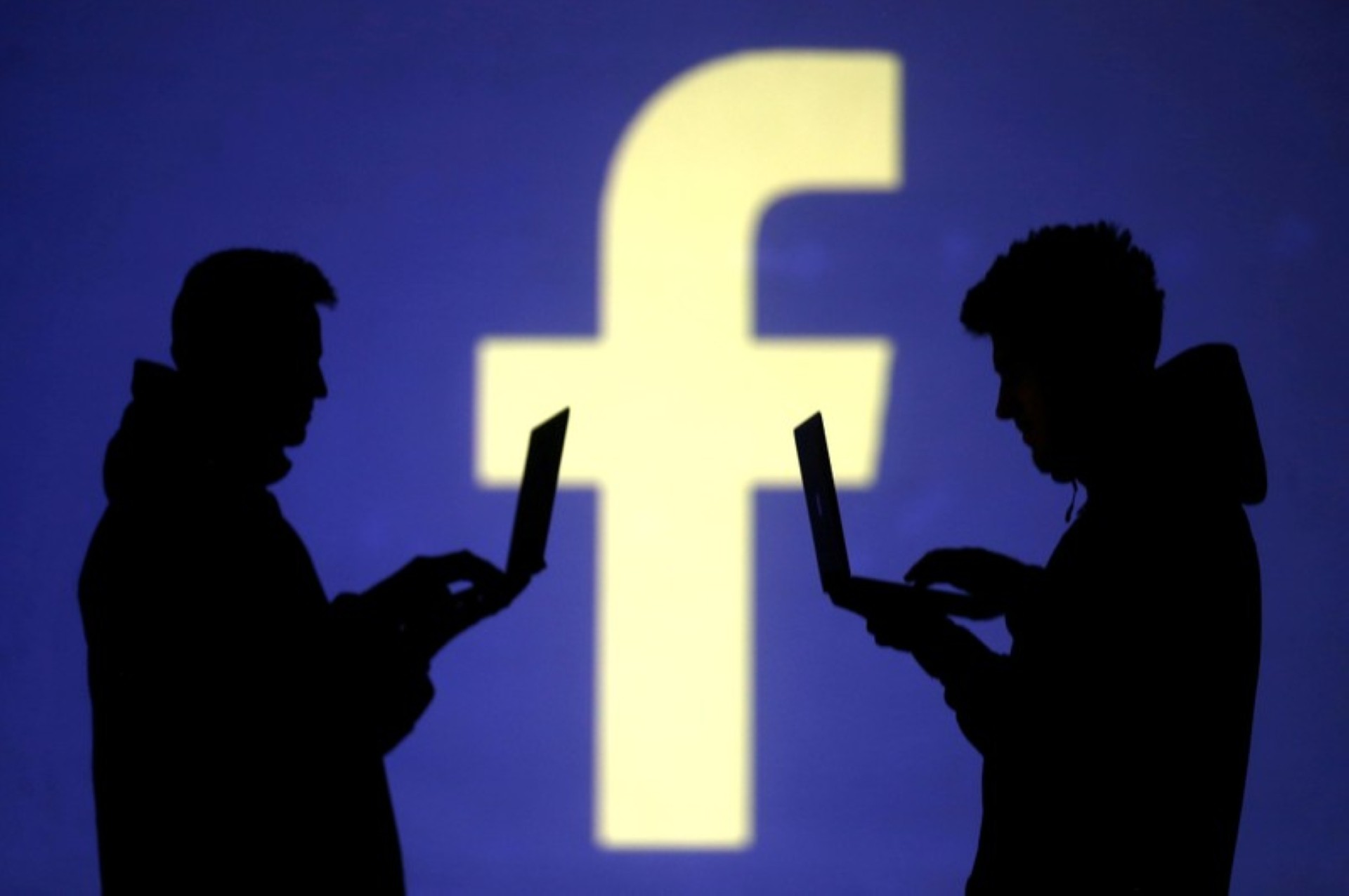 FILE PHOTO Silhouettes of laptop users are seen next to a screen projection of Facebook logo in this picture illustration taken March 28 2018.  REUTERSDado RuvicIllustration