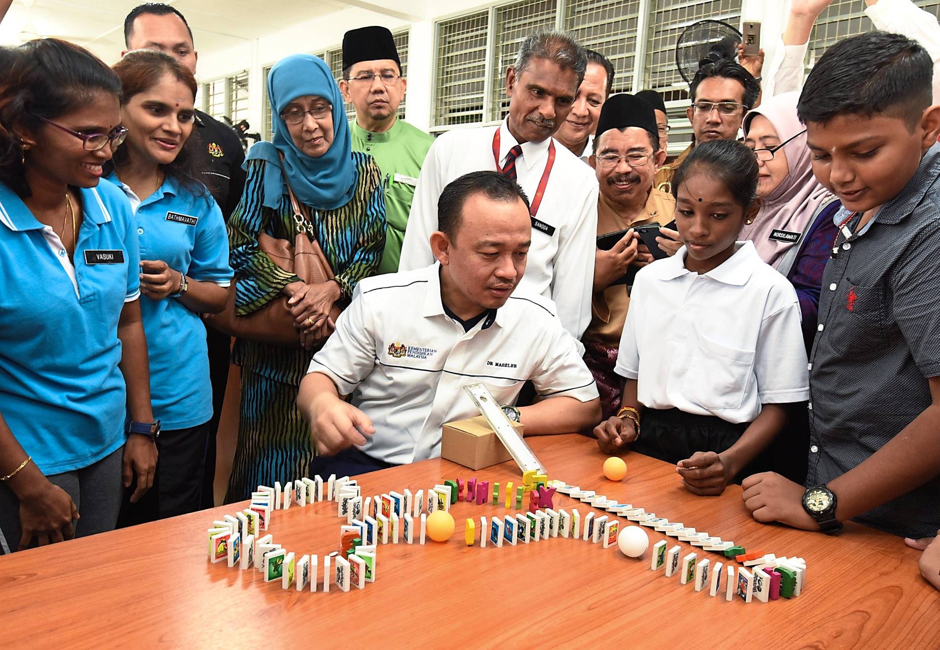 Maszlee (seated, centre) observing the demonstration on dominoes during a visit to SJK (T) Sungai Ara in Bayan Lepas, Penang.
