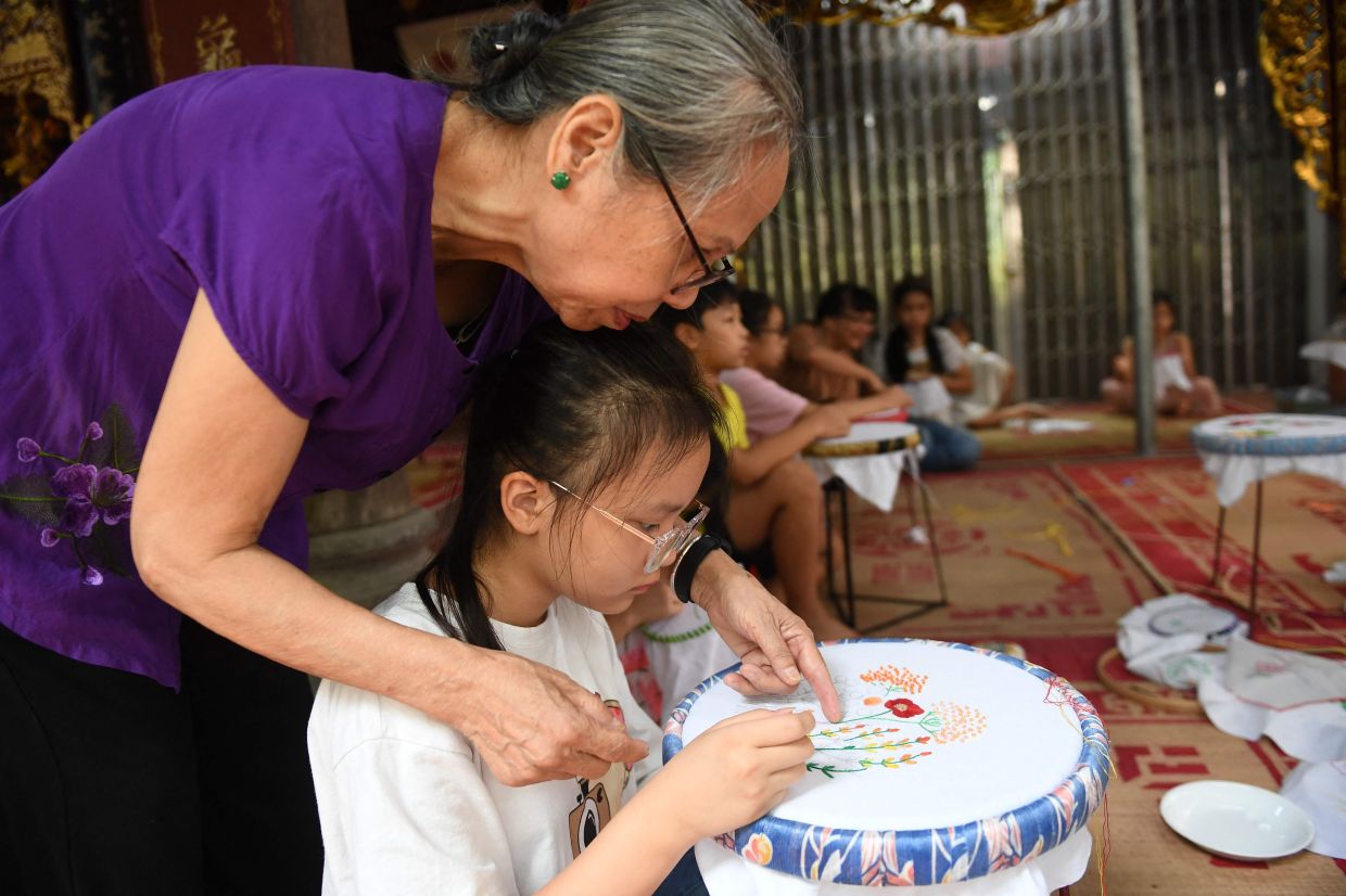 A child learns embroidery during a lesson in Hanoi on Tuesday, July 19, 2022. - AFP
