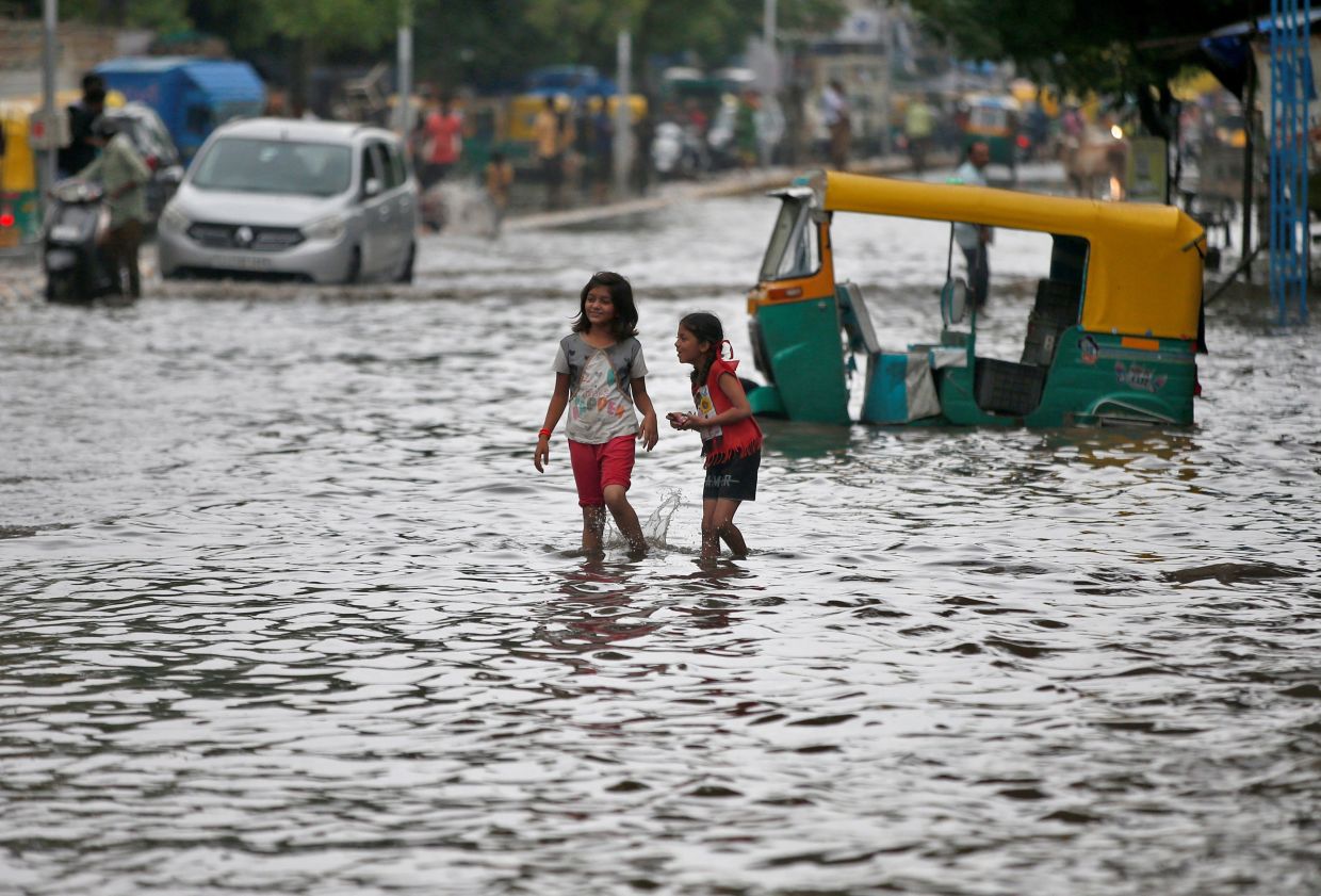 Girls wade through a waterlogged road after heavy rains in Ahmedabad, India,on Tuesday July 19, 2022. - Reuters