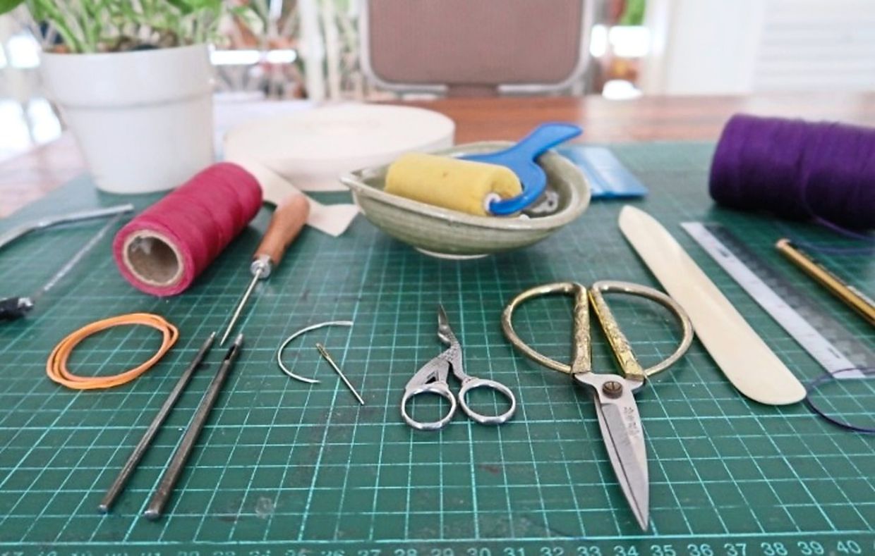 Items like waxed thread, glue, scissors, paper folder, awl, puncher, cotton tape, and needles are some of the essentials in a bookbinder’s toolkit.