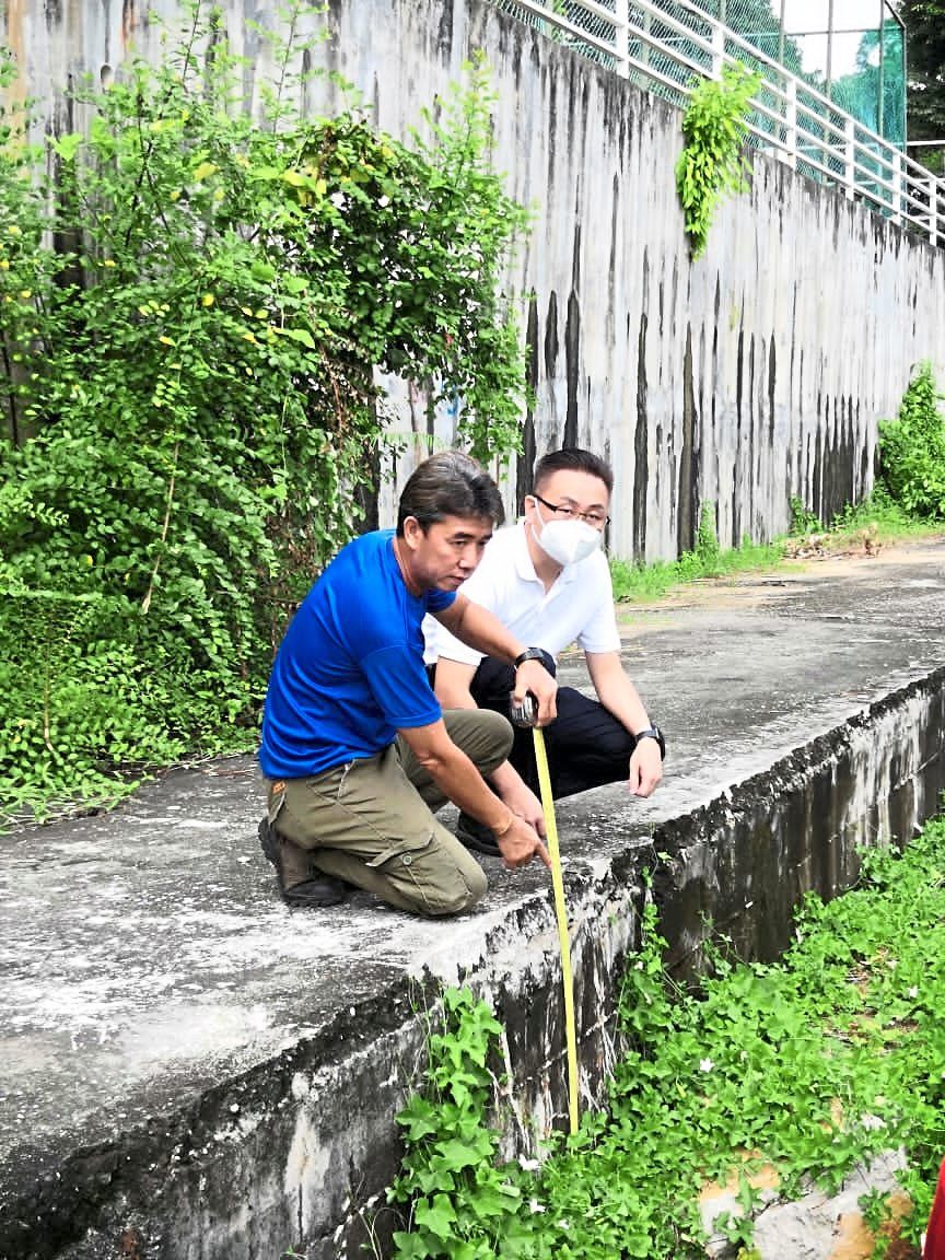 Chooi (left) and Wong measuring the depth of land subsidence near Shineville Park Condominium in Ayer Itam, Penang.