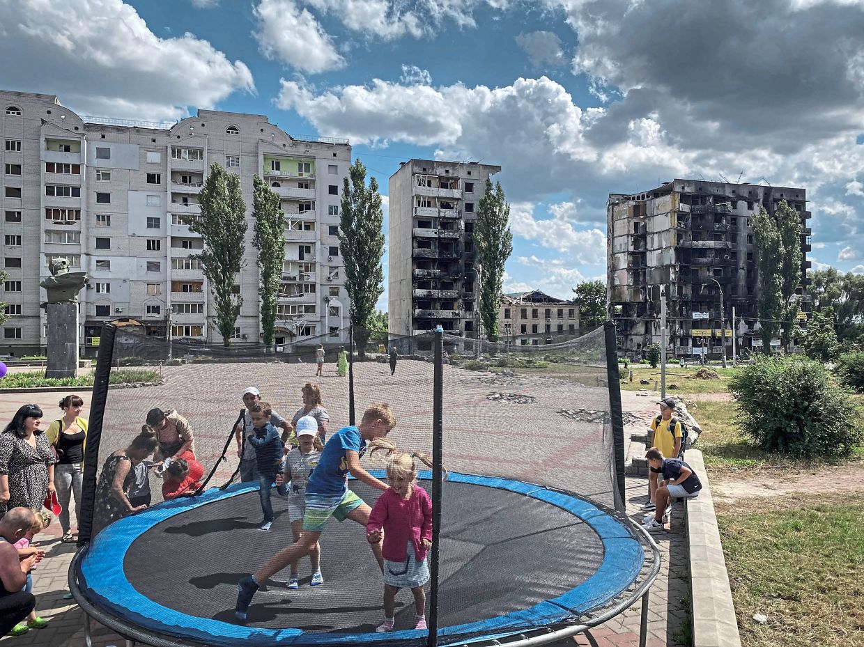 Children jumping on a trampoline against the backdrop of destroyed buildings in Borodianka.