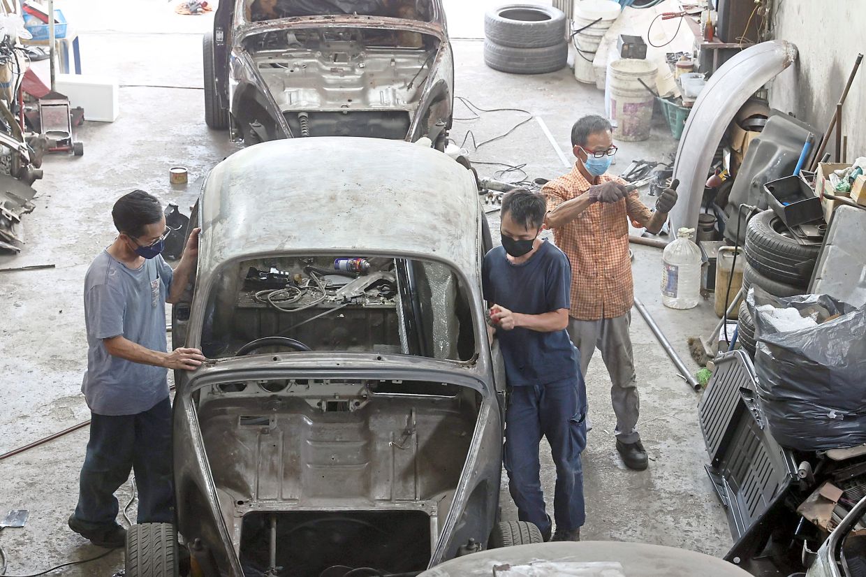 Mechanics (from left) Poon, Tang and Loi restoring and repairing an old Volkswagen. — THOMAS YONG/The Star