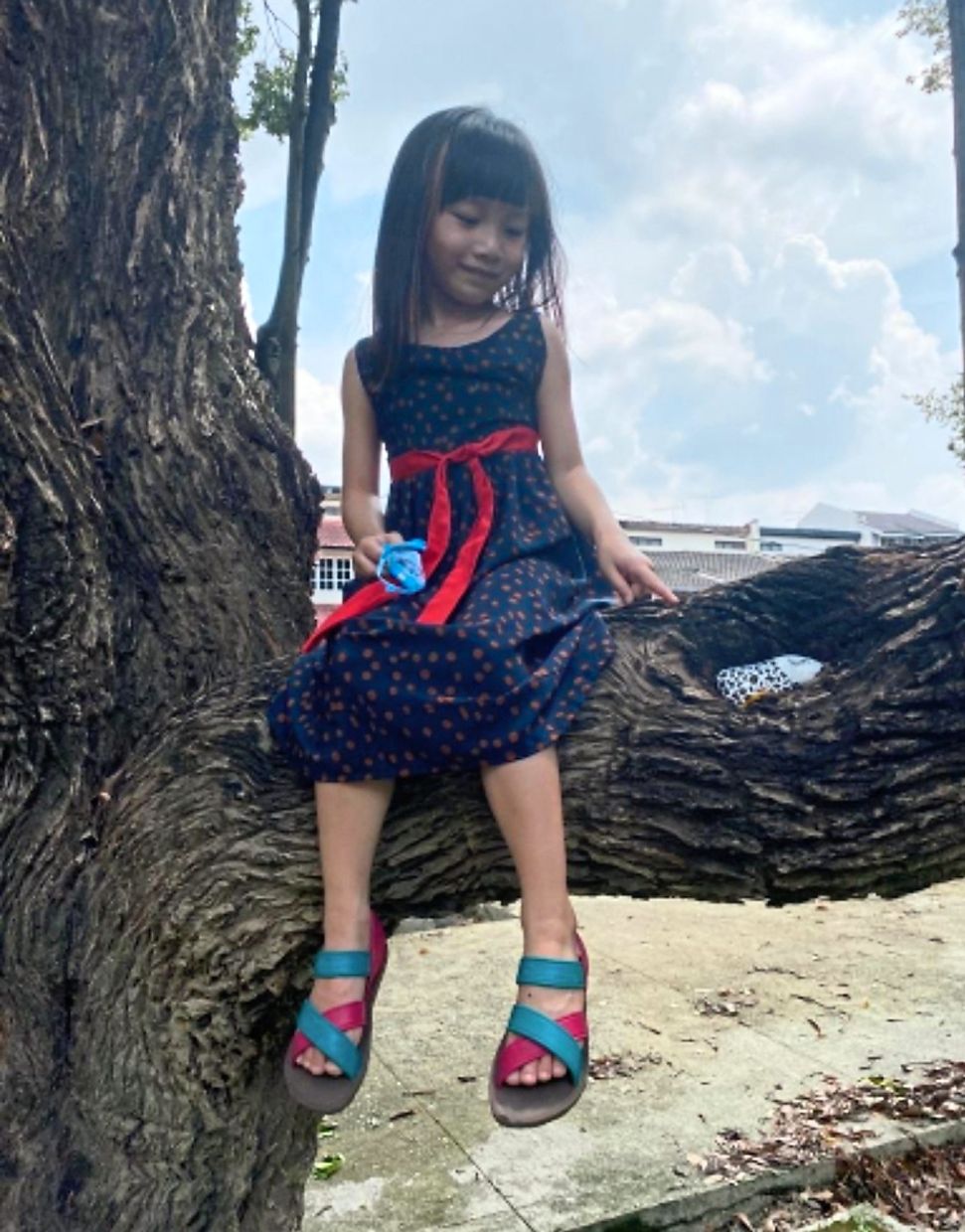 Cara with one of her father's handpainted creations which is nestled within a branch. 