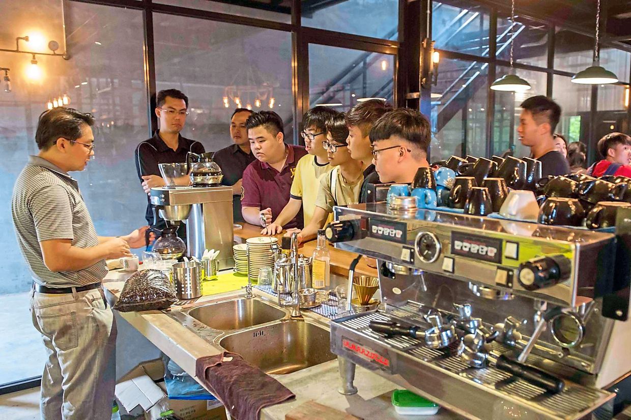 Daily grind: Businessman Jason Liew (left) brewing coffee for visitors after a tour of his factory and farm in Simpang Renggam, Johor. — THOMAS YONG/The Star