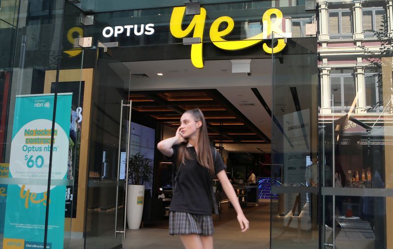 FILE PHOTO A woman uses her mobile phone as she walks past in front of an Optus shop in Sydney Australia February 8 2018. REUTERSDaniel MunozFile Photo