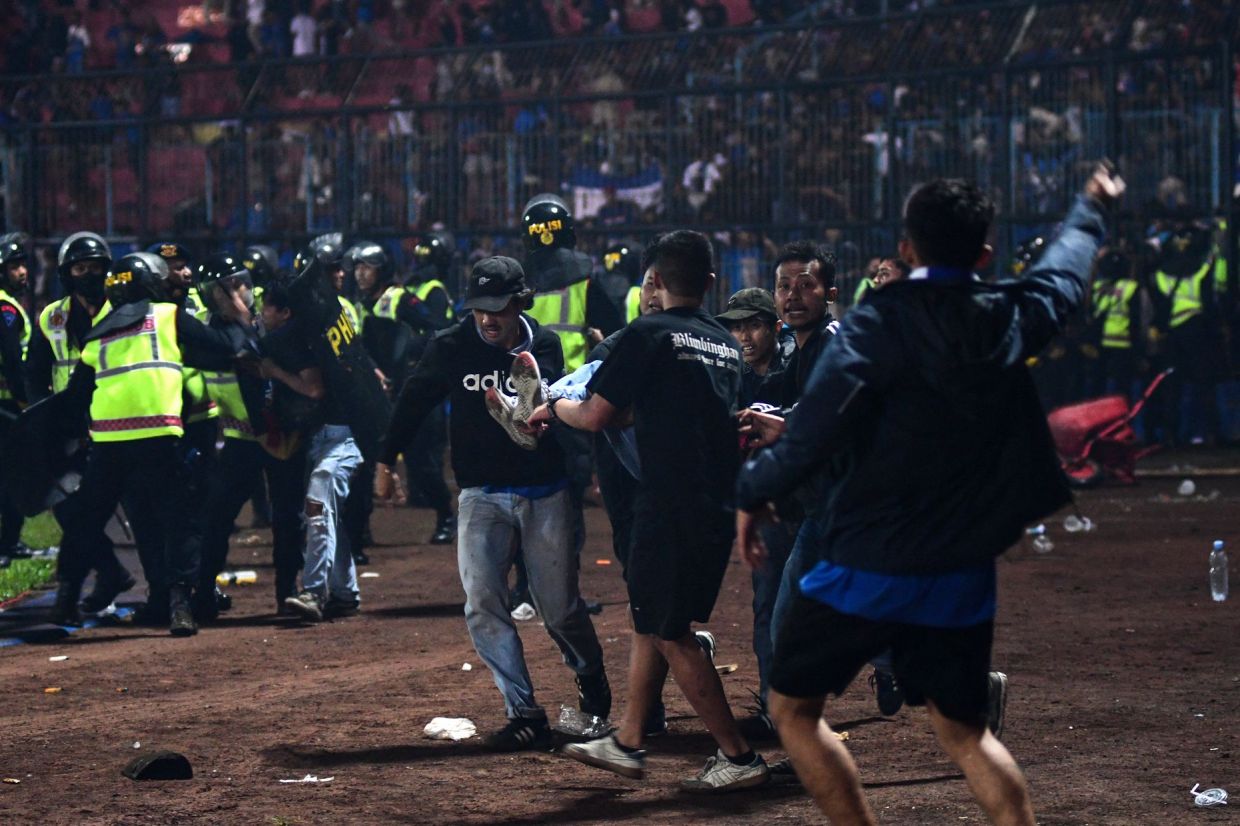 In this picture taken on October 1, 2022, a group of people carry a man at Kanjuruhan stadium in Malang, East Java. - AFP