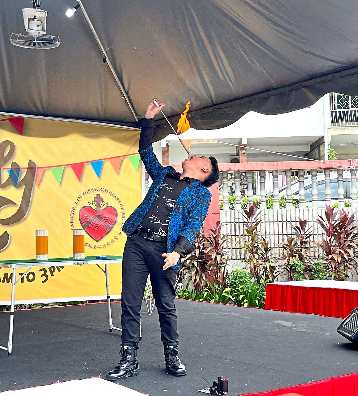 Ho wowing the audience with a fire-swallowing routine during a church family day event.