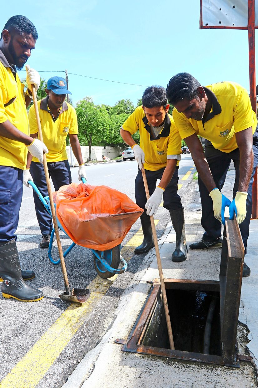 MBPP workers cleaning a drain near Pulau Tikus market and clearing floating rubbish (below) in a monsoon drain in flood-prone Jalan P. Ramlee. – Filepic