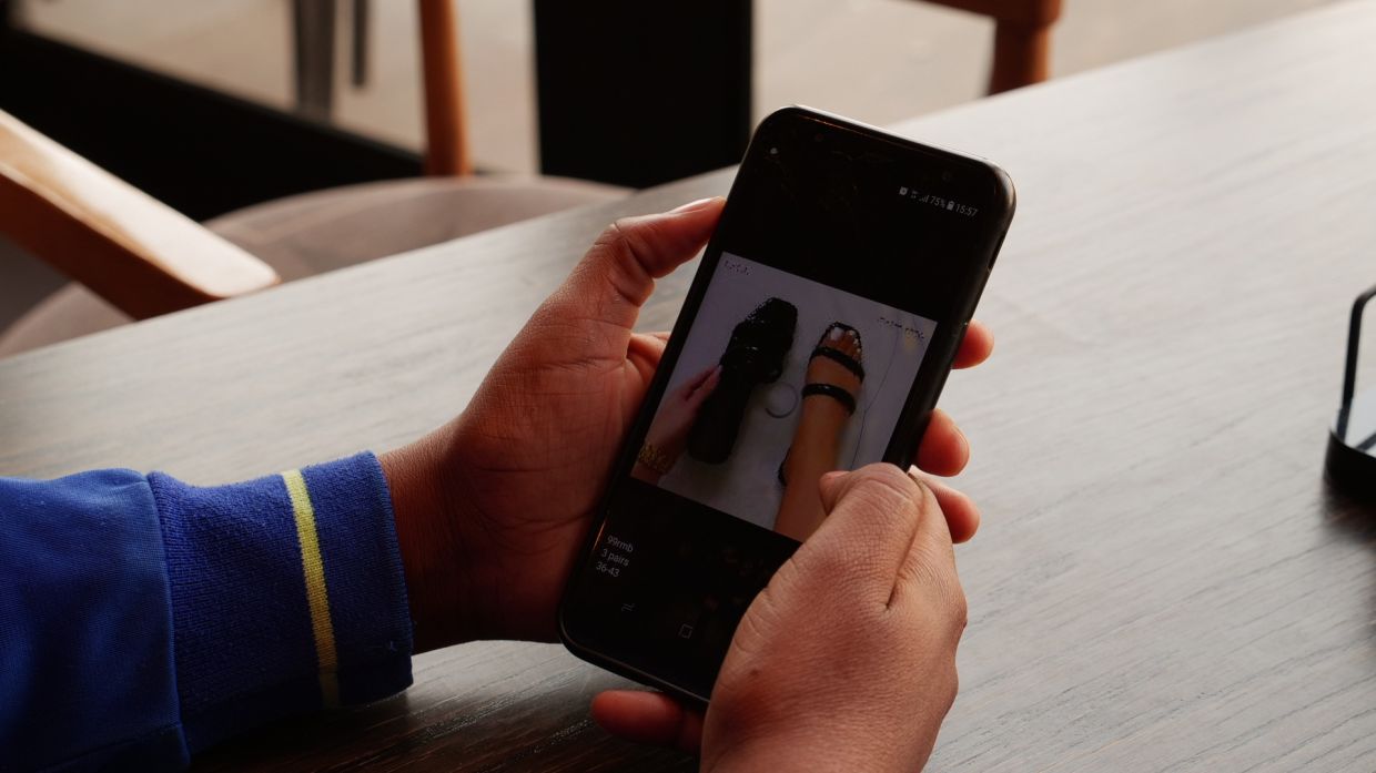 Ruth Lazarus scrolls through images of some of the shoes she is selling online while sitting at a coffee shop in Windhoek, Namibia. — Thomson Reuters Foundation/Kim Harrisberg