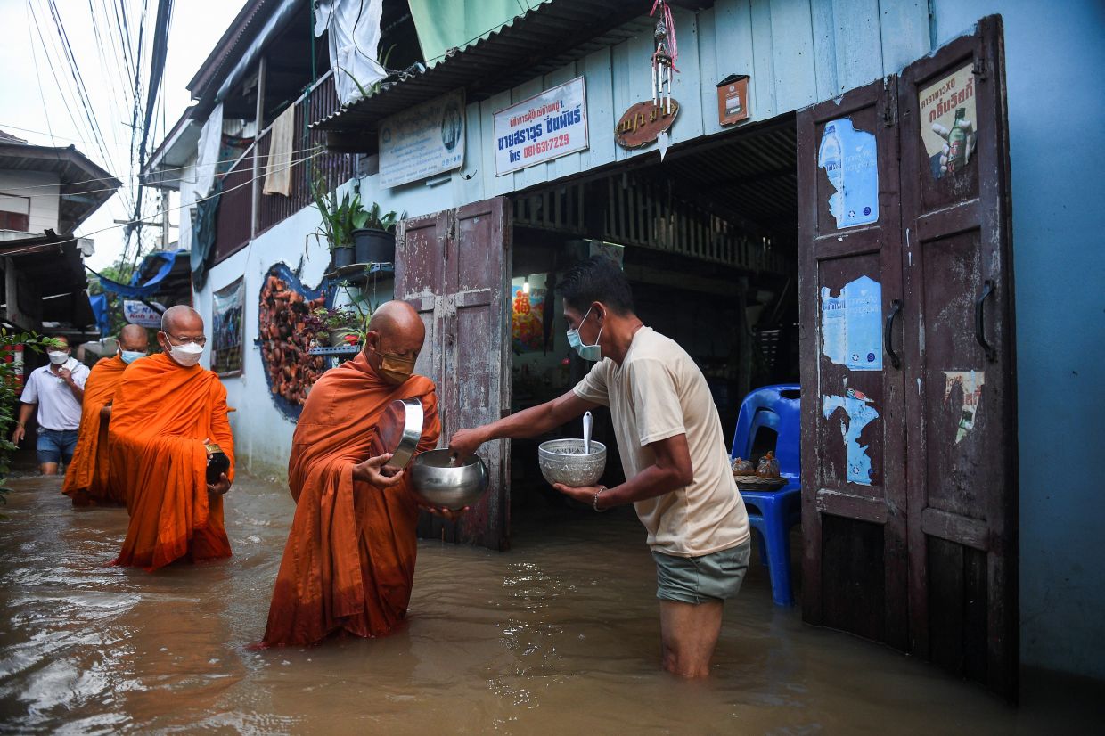 Monks walk to receive alms on a flooded street in Koh Kret in Nonthaburi, in the outskirts of Bangkok, Thailandon Tuesday, October 12, 2022. - Reuters