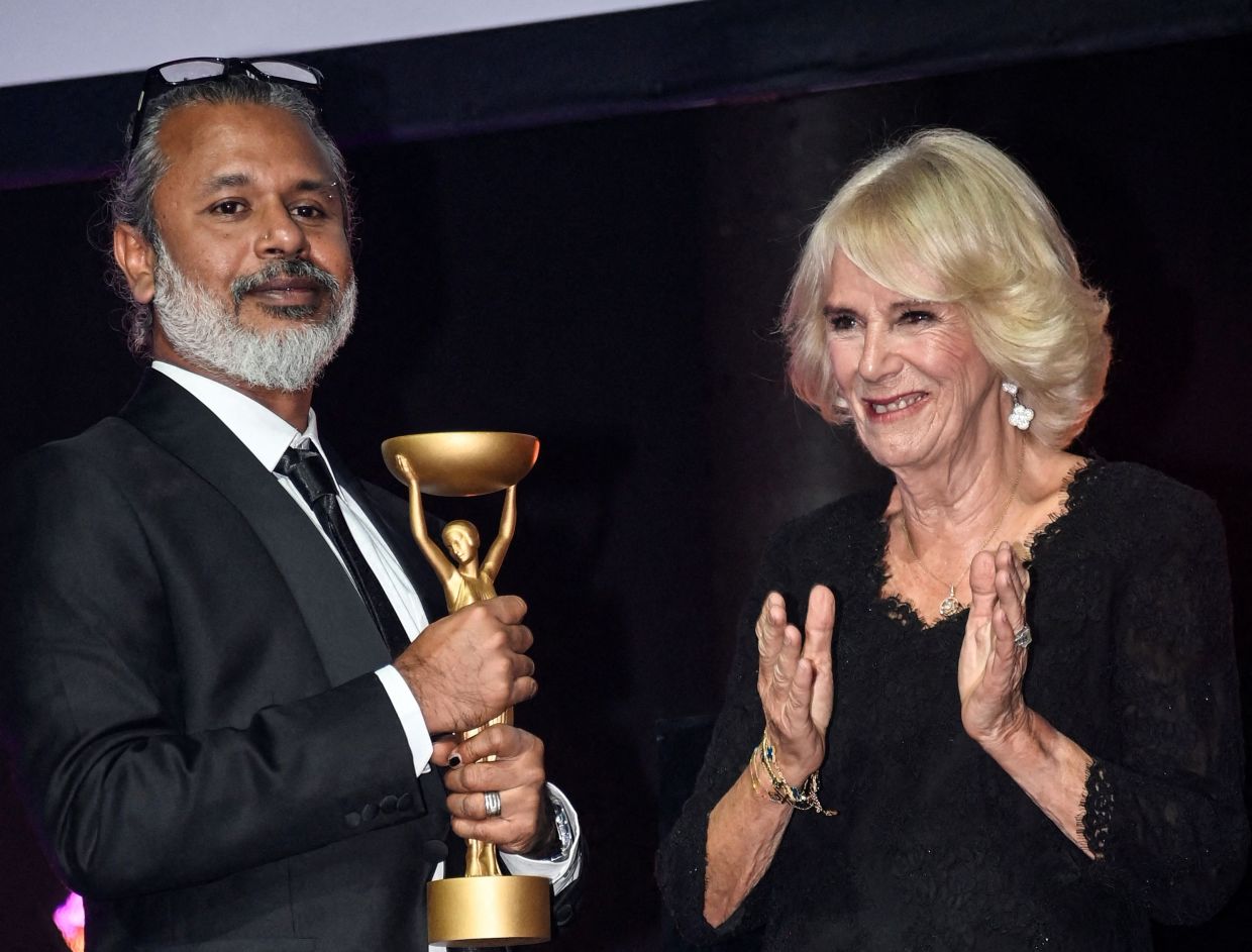 Shehan Karunatilaka poses next to Britain's Camilla, Queen Consort after winning the British Booker Prize for his novel 'The Seven Moons of Maali Almeida', during the Booker Prize for Fiction 2022 awards ceremony in London on Oct 17. Photo: AFP