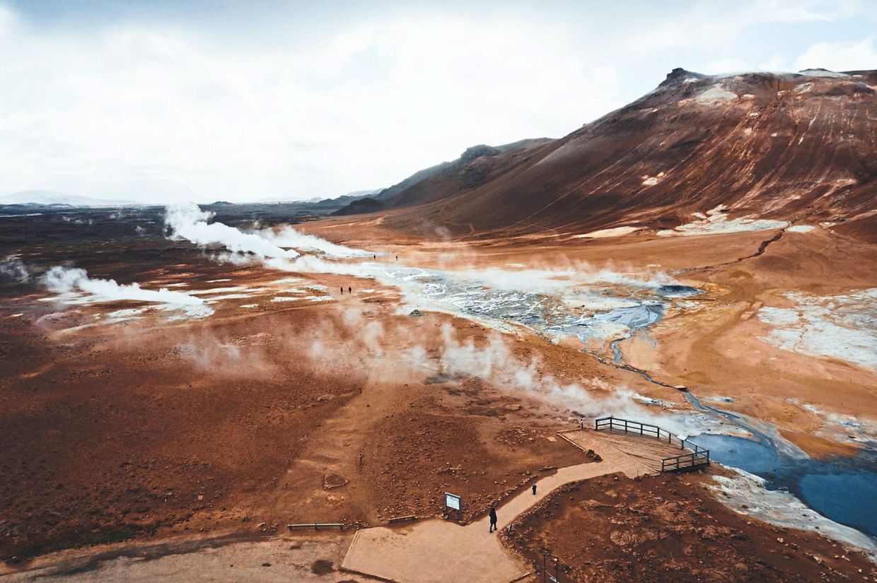 The barren lunar landscape Hverir, where bubbles and steam rise up from countless grey mud holes. – Visit North Iceland/dpa