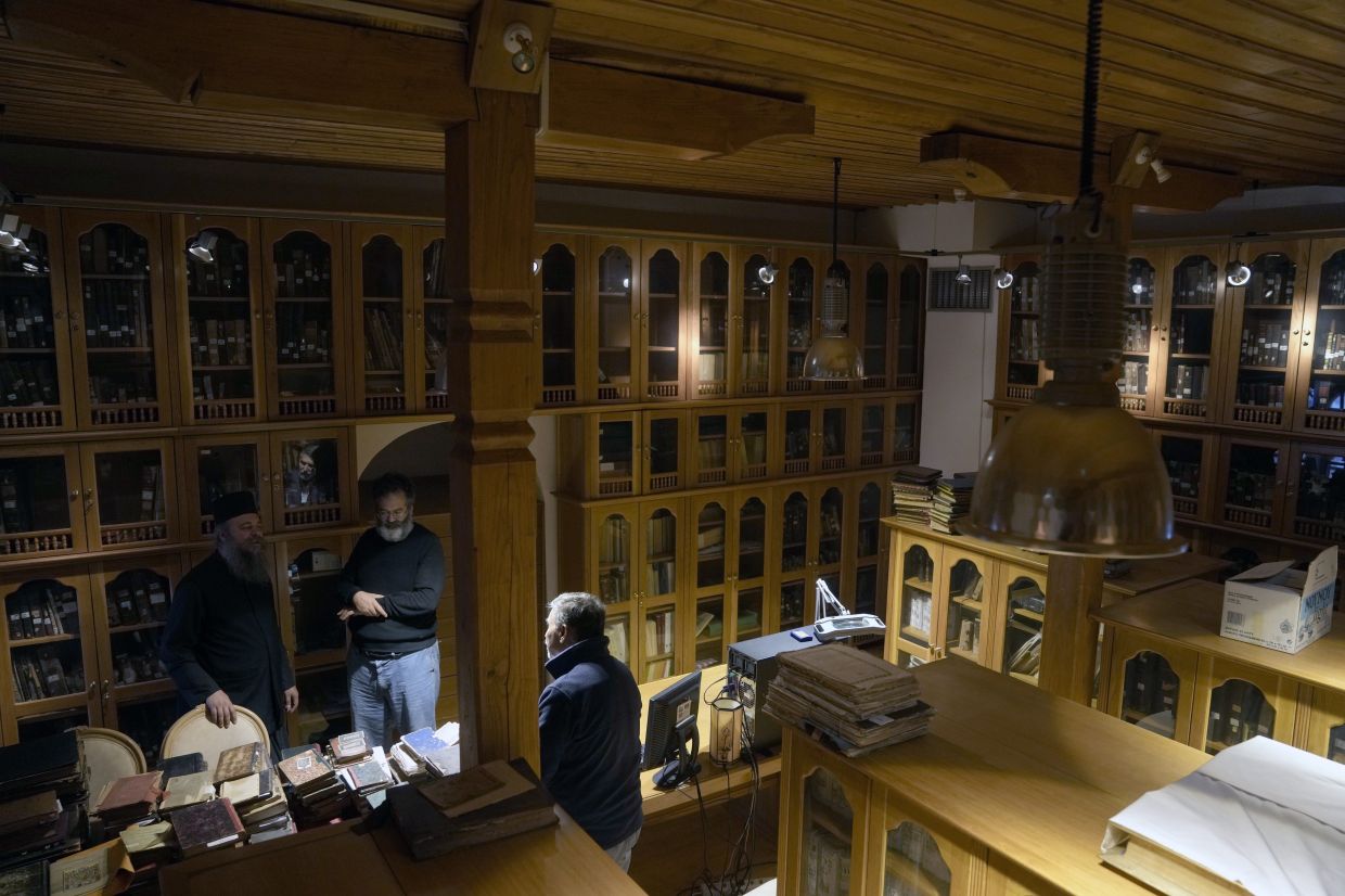 Father Theofilos, a Pantokrator monk, left, Byzantine scholar Yiannis Niehoff-Panagiotidis, centre, and Anastasios Nikopoulos, a jurist and scientific collaborator of the Free University of Berlin, speak to each other at the library of Pantokrator Monastery in the Mount Athos, northern Greece. Photo: AP