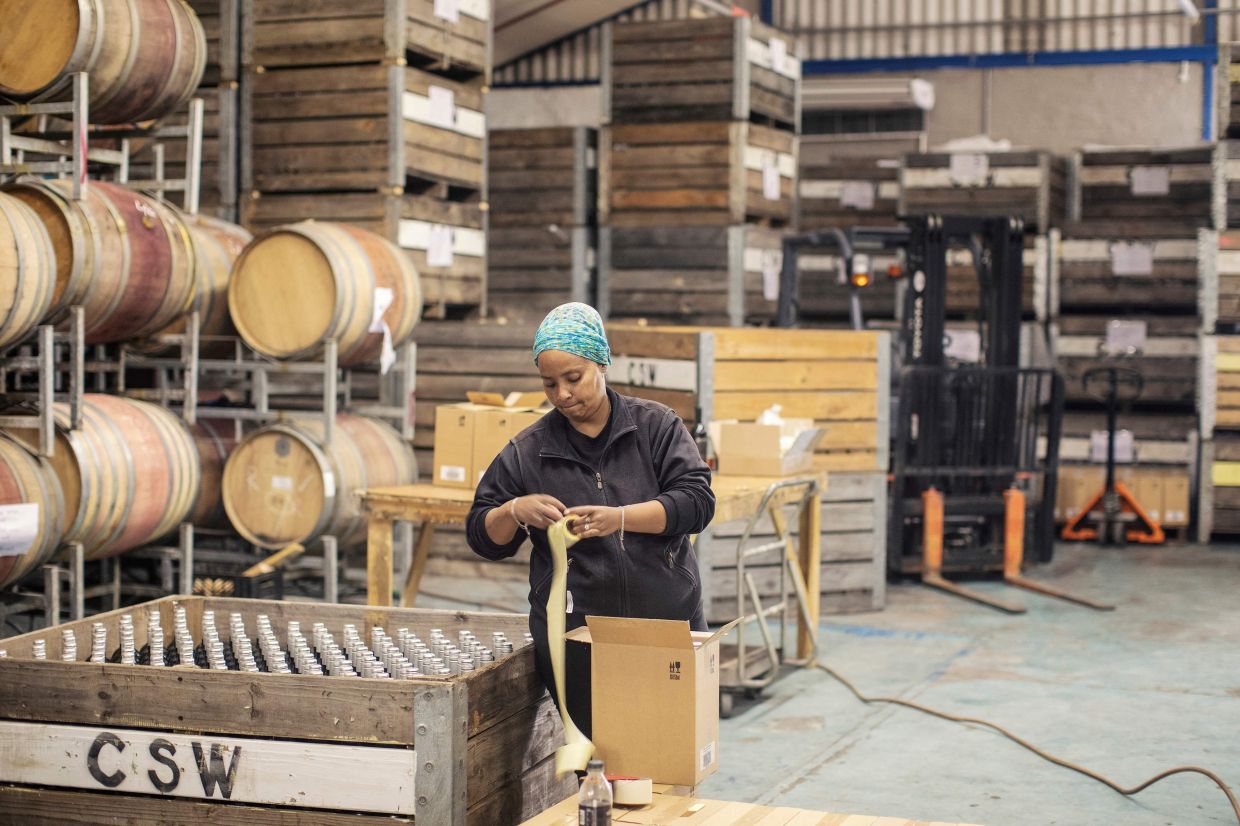 A worker labelling bottles at Stevens' winery in South Africa.