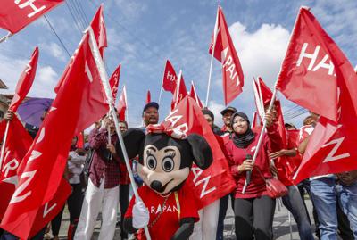 A supporter in a Minnie Mouse costume raises a PH flag alongside other attendees during nomination day at Petra Jaya in Sarawak. — ZULAZHAR SHEBLEE/The Star