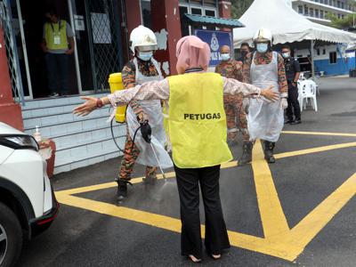 Fire and Rescue Department personnel disinfecting an election worker after Covid-19 patients had cast their ballots during early voting at the Bentong police headquarters. — ART CHEN/The Star