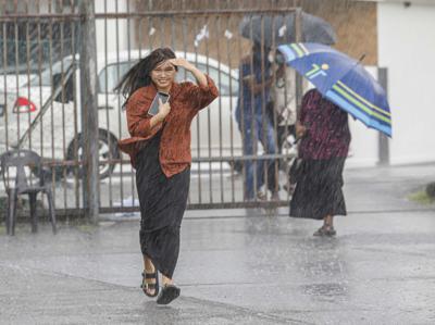 A voter running for shelter as a sudden downpour hits the Batu Kawa community hall in Kuching. – ZULAZHAR SHEBLEE/The Star