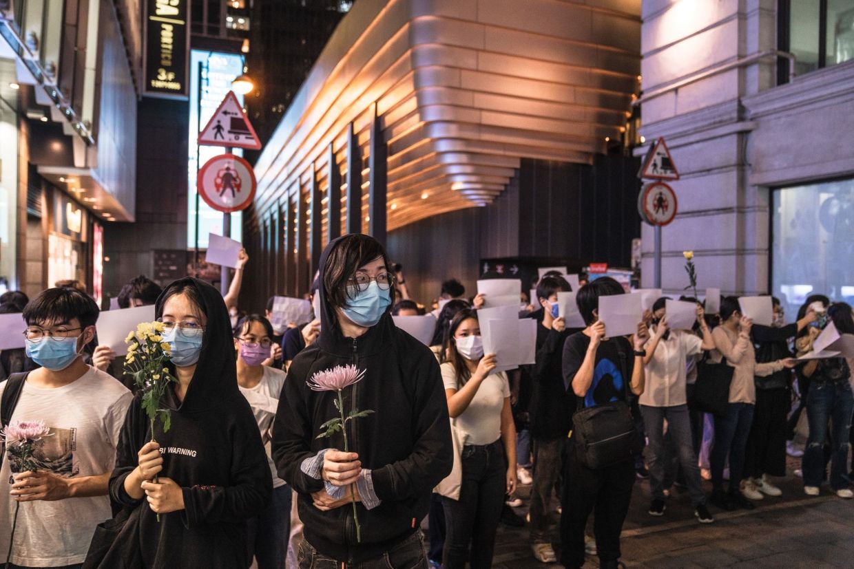 Demonstrators hold blank protest signs during a vigil commemorating victims of China's Covid Zero policy in Hong Kong, China, on Monday, Nov. 28, 2022. Dozens of people in Hong Kong rallied in the city and emulated some of the protests erupting in China in opposition to the nation’s Covid Zero policy. - Bloomberg