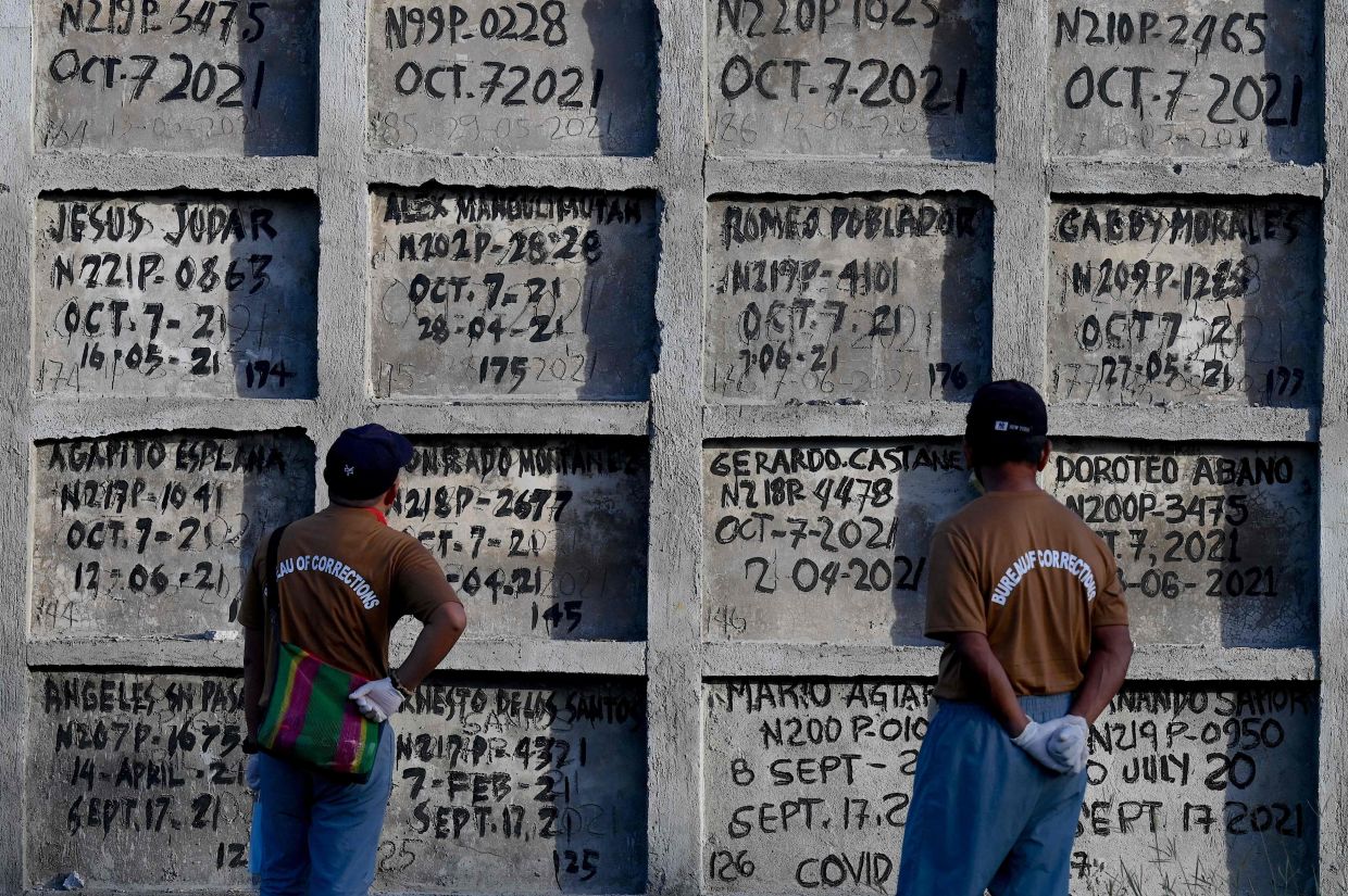 Prison inmates look at tombs during a mass burial of 70 unclaimed bodies of prisoners at New Bilibid Prison Cemetery in Muntinlupa, metro Manila on Friday, December 2, 2022. - AFP