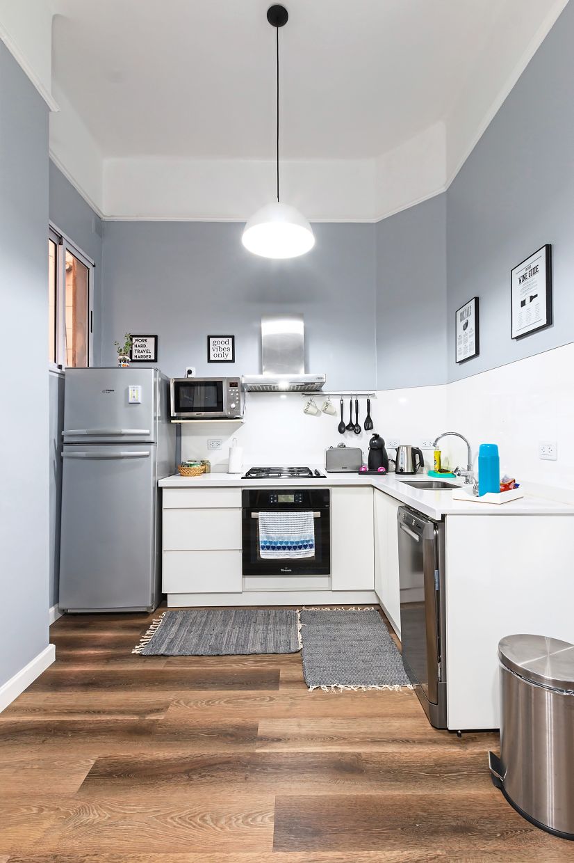 A down light produces a focal point while the tall ceiling creates an illusion of space in this narrow Scandinavian-style kitchen.