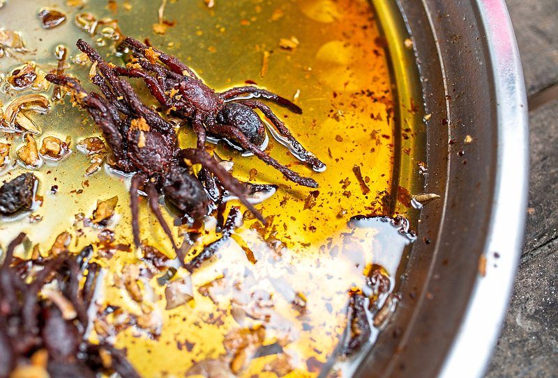 Two fried tarantulas in golden oil at Oudongk market.