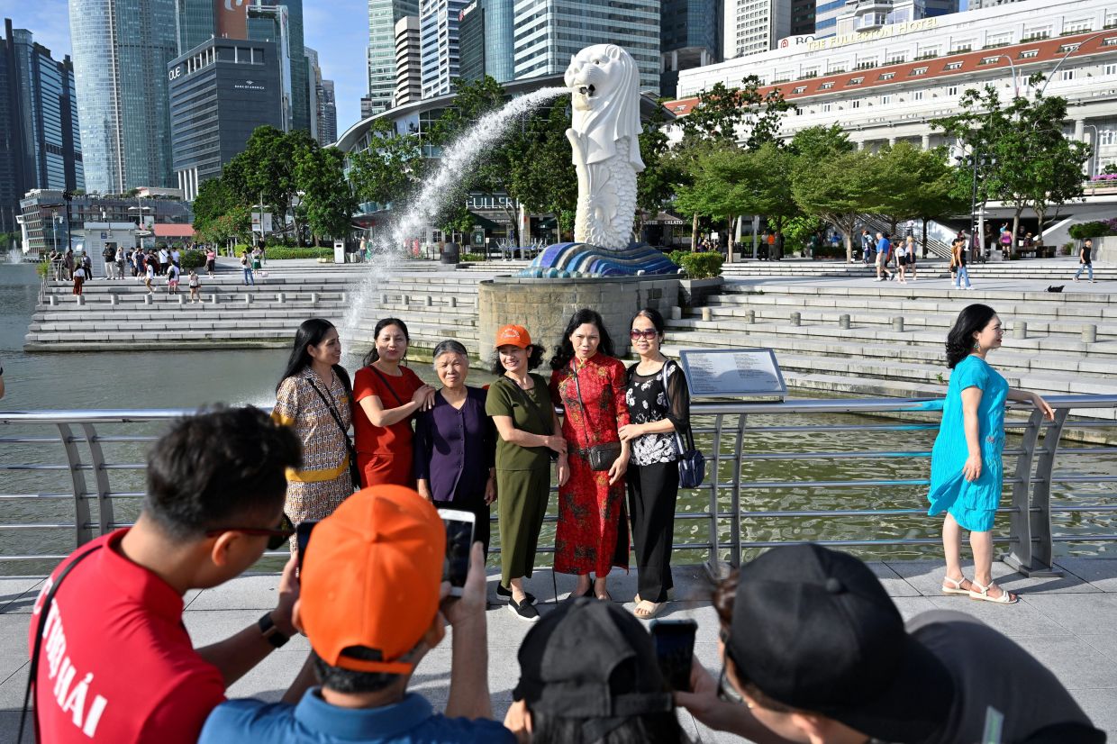 Tourists pose for photographs at Merlion Park in Singapore on Friday, January 27, 2023. - Reuters