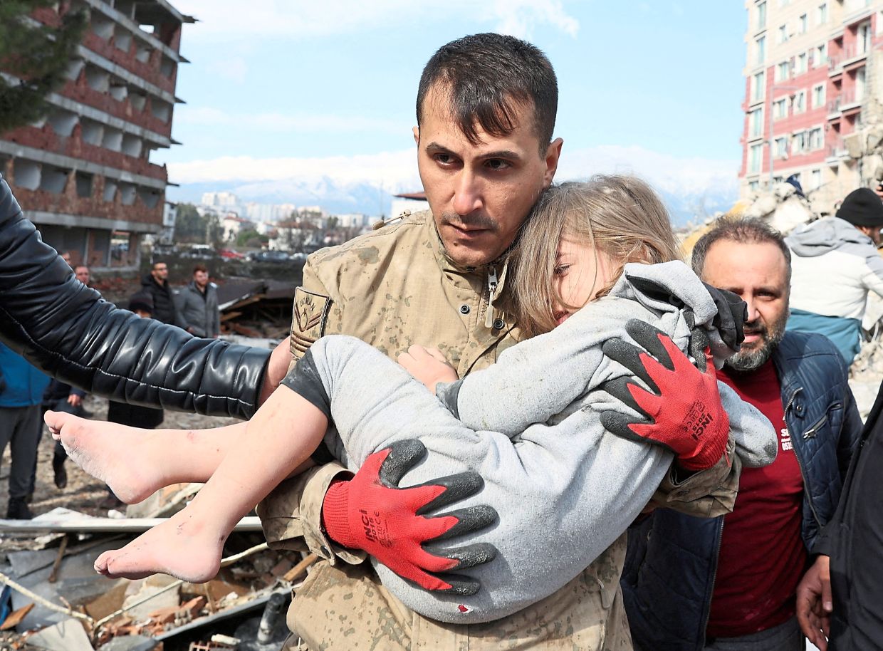 Lucky to be alive: Muhammet Ruzgar, five, is carried out by a rescuer in Hatay, Turkiye. — Reuters