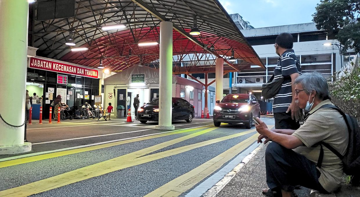 Horrific tragedy: Media personnel waiting outside of the emergency department at HKL. (Below) Firefighters had to use rescue tools to remove the pinned victims from the wreckage. — CHAN TAK KONG/The Star/China Press