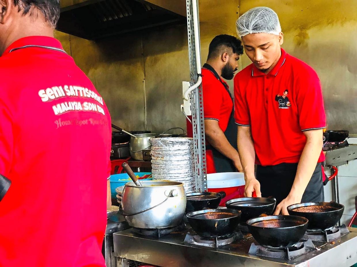 Workers preparing piping hot spicy claypot meals at the stall.