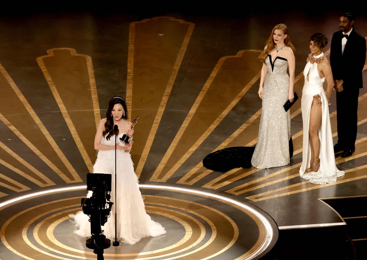 Michelle Yeoh accepts the Best Actress award from Jessica Chastain and Halle Berry onstage. Photo: AFP