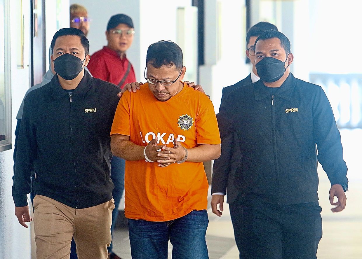 Busted: MACC officers ushering Mohd Hussein at the Kuala Lumpur Magistrate’s Court. — FAIHAN GHANI/The Star