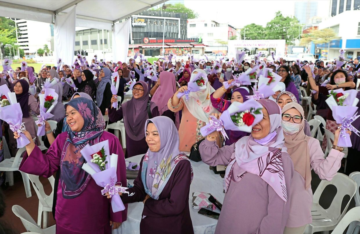 Guests holding the flowers given to them, while enjoying the entertainment during the MBPJ Women’s Day celebration.