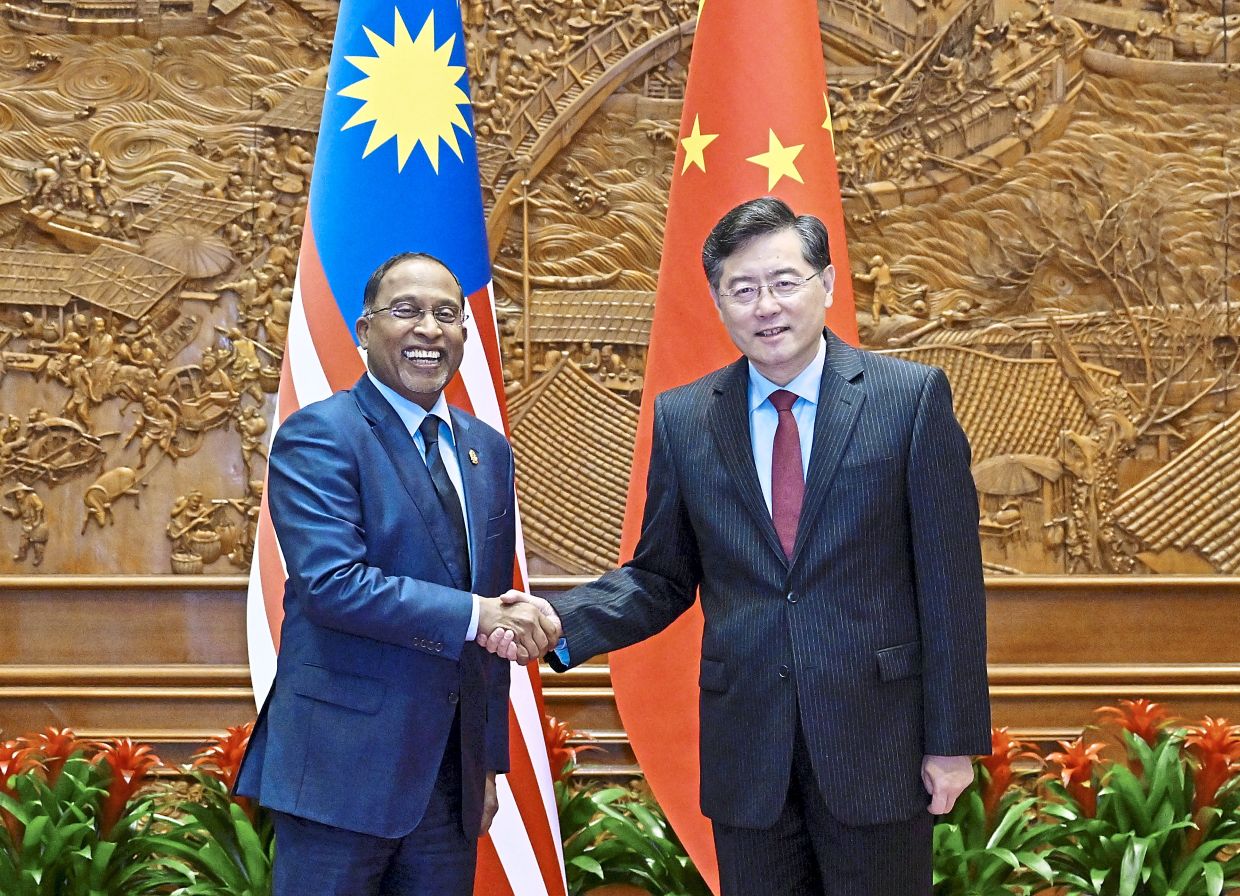 Forging ties: Zambry shaking hands with his counterpart Qin Gang in Beijing.