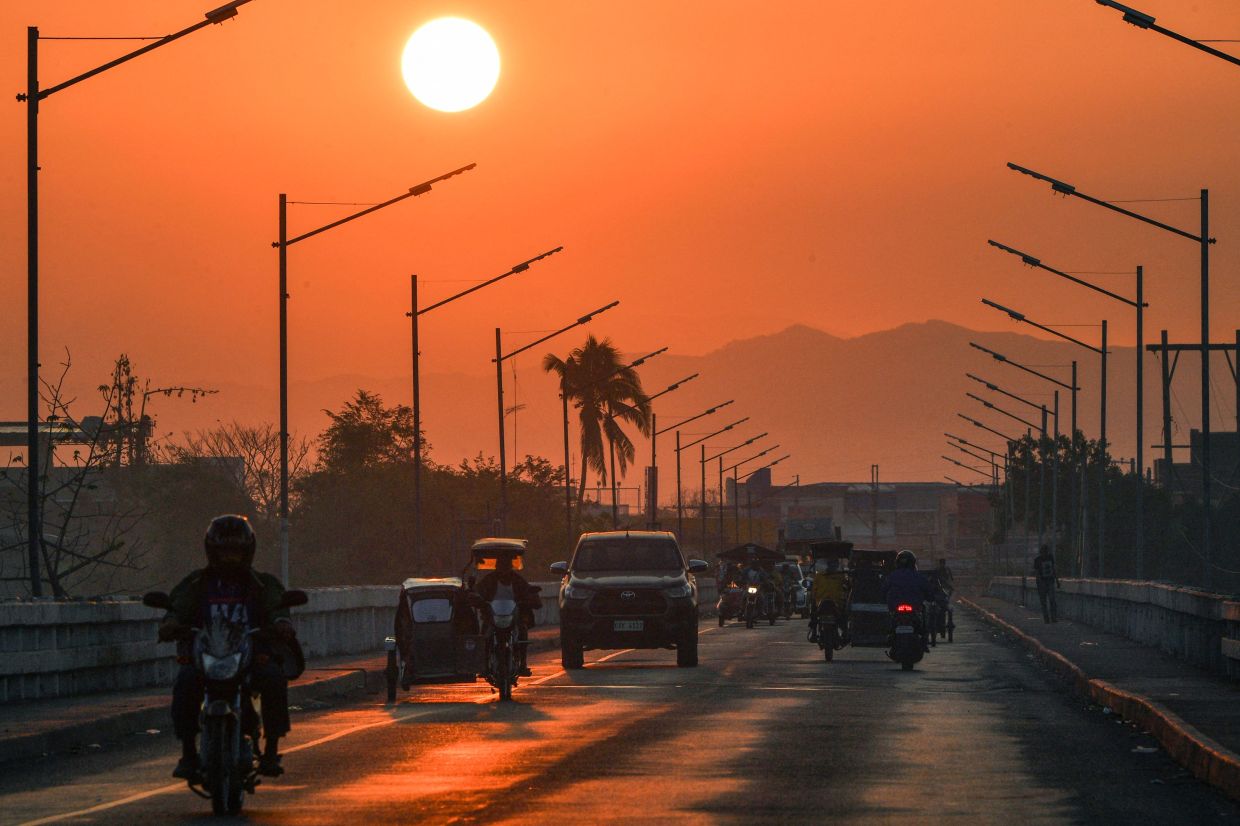 Motorists crossing a bridge as the sun rises in Sta Rosa town, Nueva Ecija province north of Manila. - AFP