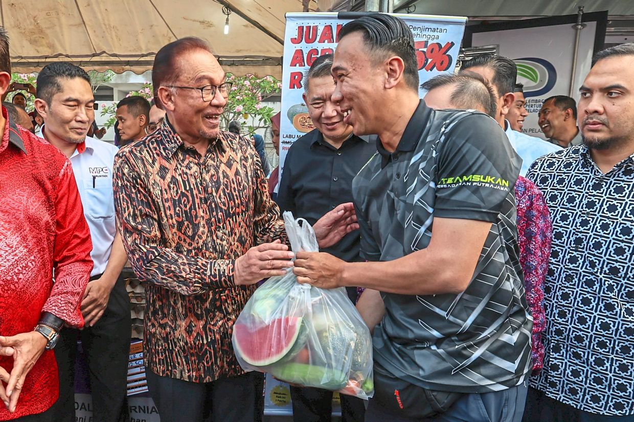 Straight from the farm: Anwar gifting a bag of fresh produce to a visitor after launching the Agro Rahmah Sales at the Ramadan bazaar in Putrajaya yesterday. — Bernama