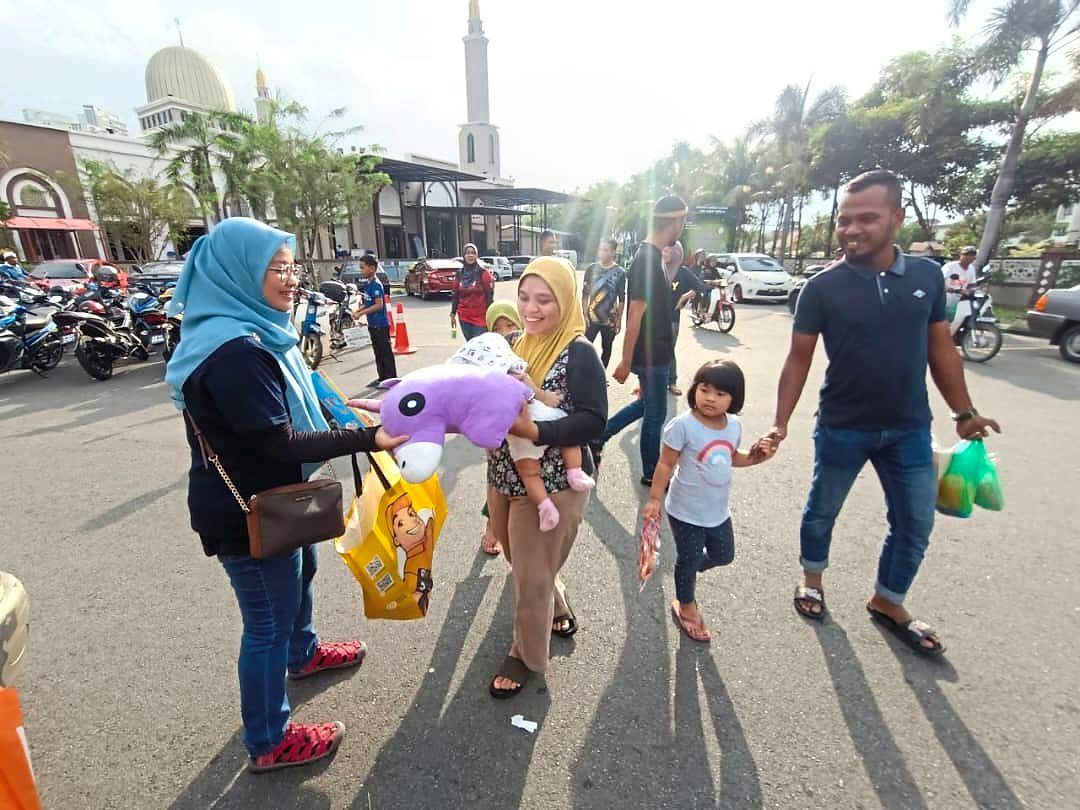 A parent at the Ramadan bazaar in Kubang Semang accepting toys from a volunteer.