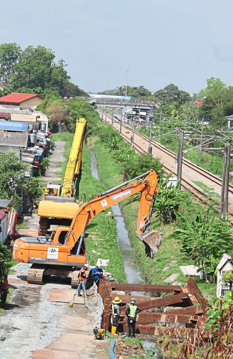 Heavy machinery at the monsoon drain in Taman Melawis, Klang, parallel to the rail tracks. — Photos: KK SHAM/The Star
