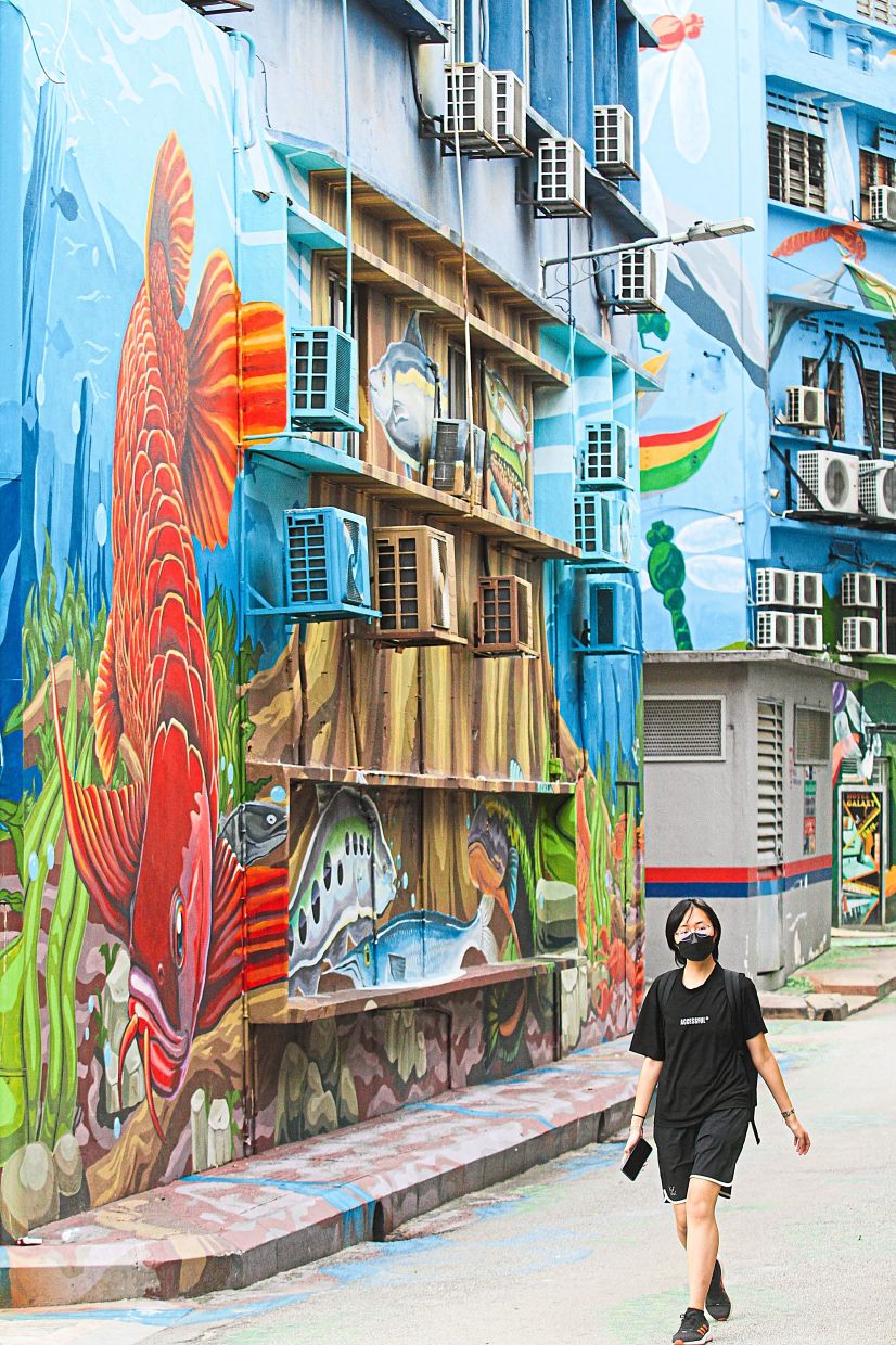 A woman walks past an eye-catching mural with aquatic elements.