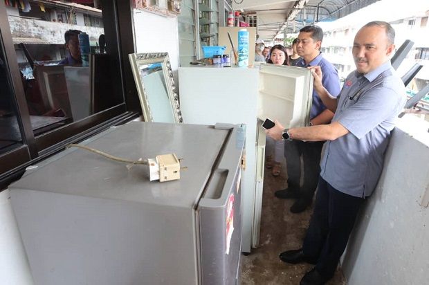 Johor Housing and Local Government Committee chairman Datuk Mohd Jafni Md Shukor (right) looking at a broken refrigerator that was dumped on the third floor of the Taman Ungku Tun Aminah Flats, Johor Baru.