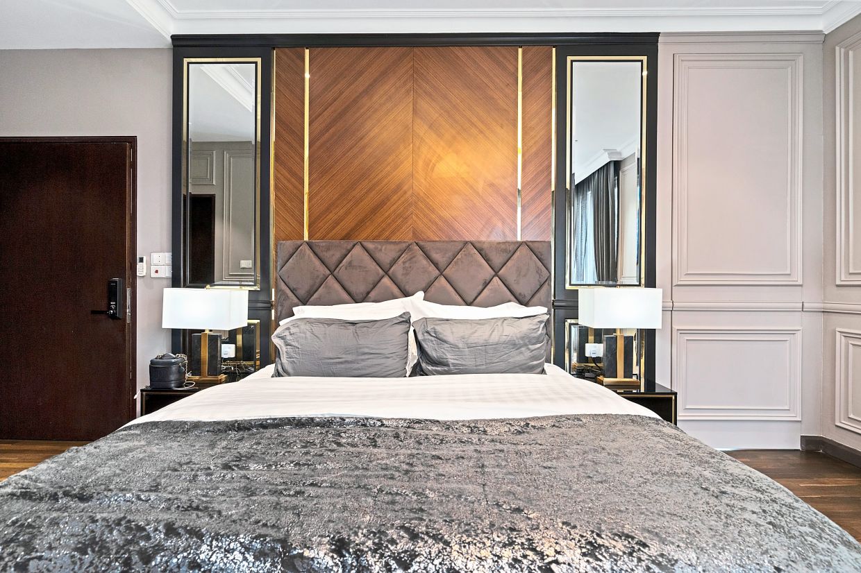 In the master bedroom, a refined wooden background adorns the wall behind the lush bed, creating a sophisticated visual effect.