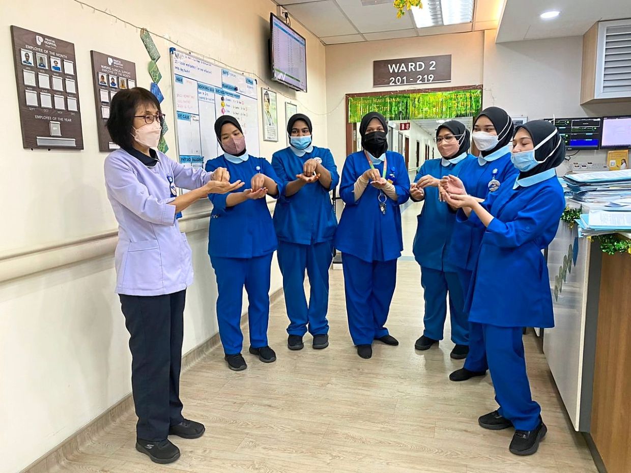 Ng (left) teaching junior nurses the proper way to wash and sanitise their hands, as part of her duties in her hospital's infection control unit. — NG SIEW IM