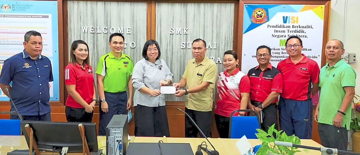 Johnady (centre) presenting the donation from SDNU Sibu branch to Wong.
