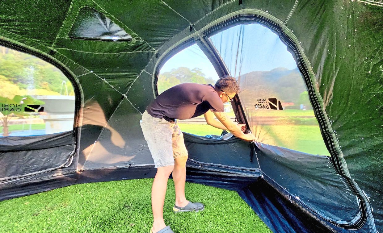 Lam Meng Tuck opening the windows in the tent after pitching it to let air in while leaving the mesh nets on to keep mosquitoes out. This dome tent is almost 2m tall, allowing people to comfortable stand up inside.